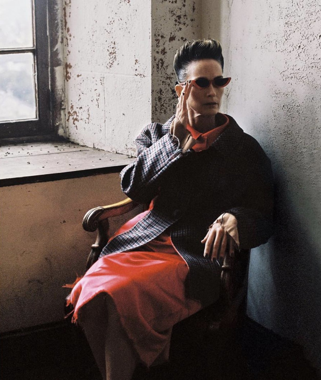 Fashion editorial portrait, tailored coat and sunglasses by a window